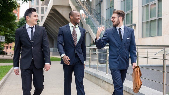 Three men in suits talking and walking together outside