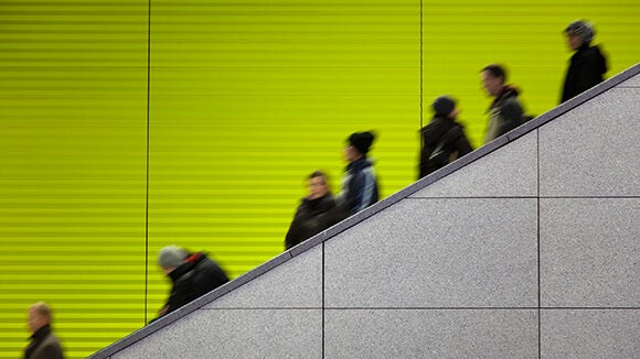 Escalator against green wall with commuters 