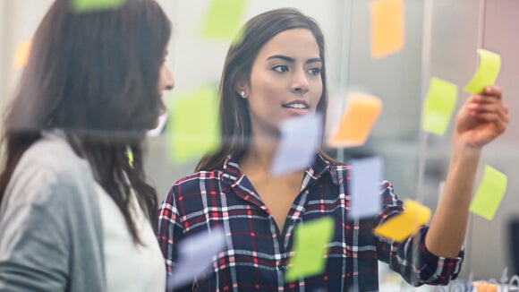 Young women looking at postnotes young-business-women-looking-at-postnotes