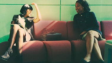 Two women sitting on a couch together talking