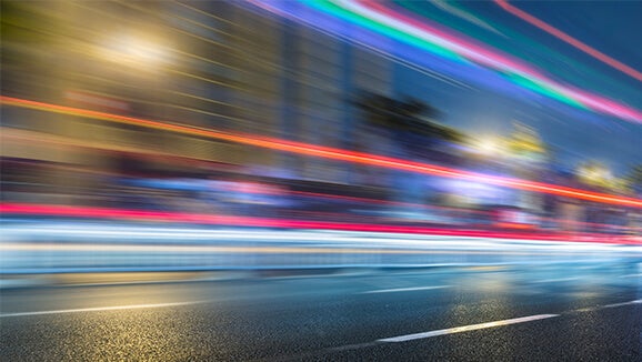Cars driving by at high speed leaving a trail of light