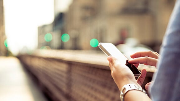 Woman walking on the street typing on her phone