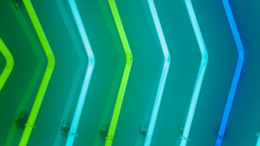 Columns of neon lights representing arrows in different shades of green and blue