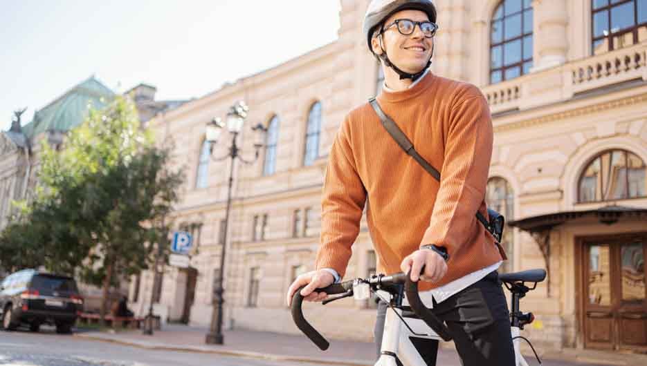 A male cyclist in a helmet is a teenager freelancer going to the office for work Monday on a bicycle eco transport in the city.