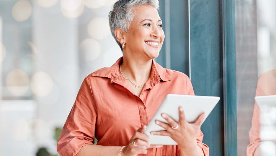 Tablet, thinking and senior business woman in office contemplating, research or internet browsing. Technology, ideas or happy elderly female with touchscreen by window for networking or web scrolling.