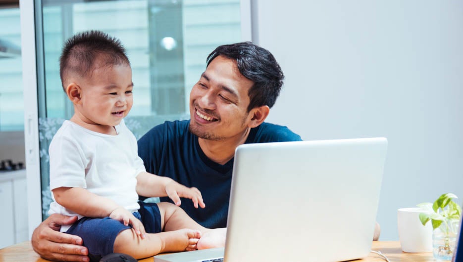 Man father working on laptop computer with son from home