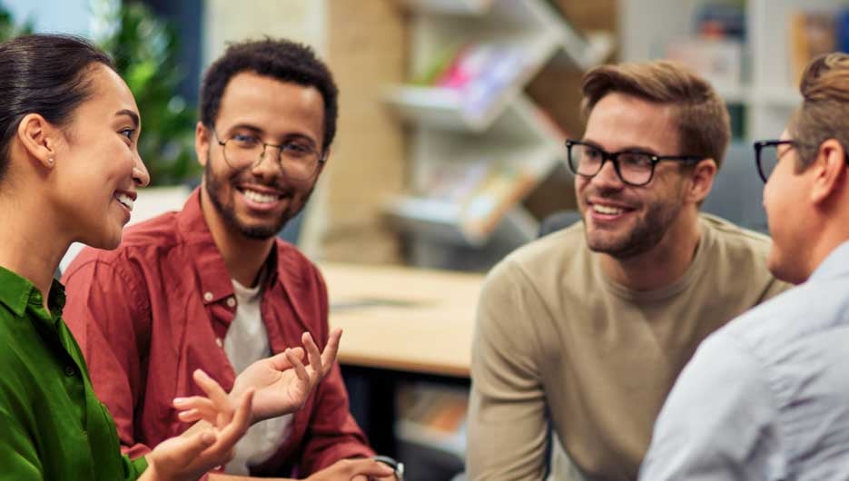 Creating success. Group of young happy multi racial business people communicating and sharing ideas while working together in the modern office. Teamwork and cooperation concept