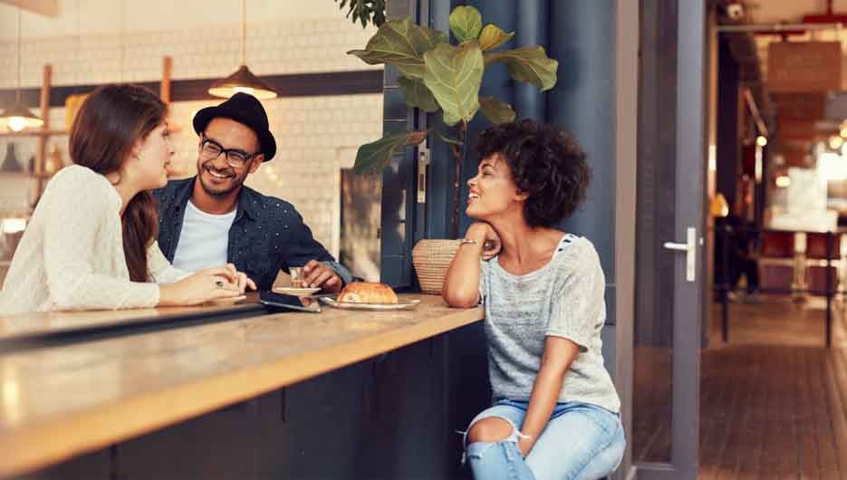 Portrait of three young people sitting together at a cafe. Group of young friends meeting in a coffee shop.